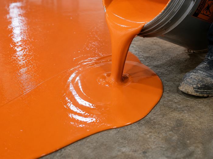 Orange epoxy being poured onto prepared concrete